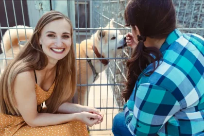 A woman sits in a cage with a dog, highlighting the emotional bond formed through shelter pet adoption.